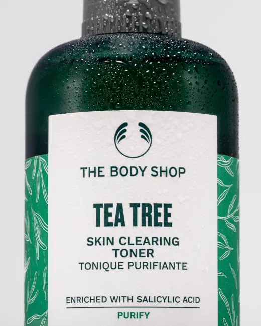 Close-up of The Body Shop Tea Tree Skin Clearing Toner, droplets on bottle against clean backdrop.