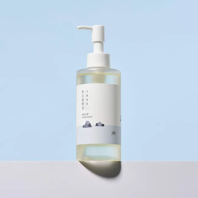 Clear bottle with pump dispenser, minimalist label, Korean text, pale blue background