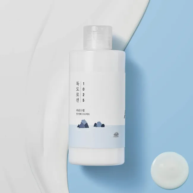 Clean skincare bottle with minimalist design, featuring Korean text and mountain illustration on a blue background.