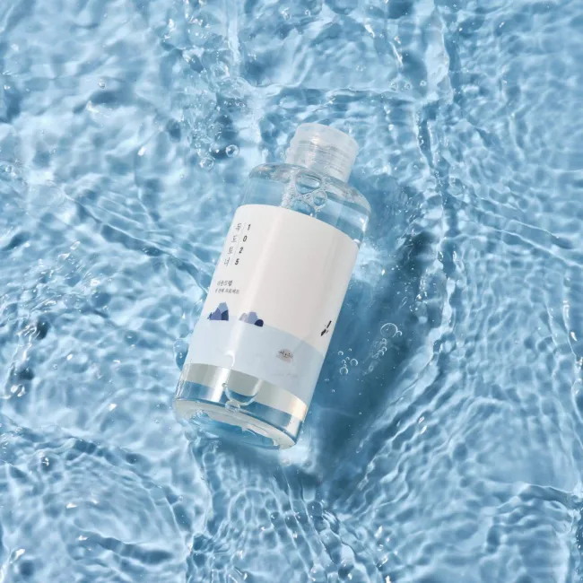 Clear skincare toner bottle in rippling water, showcasing clean beauty with natural ingredients