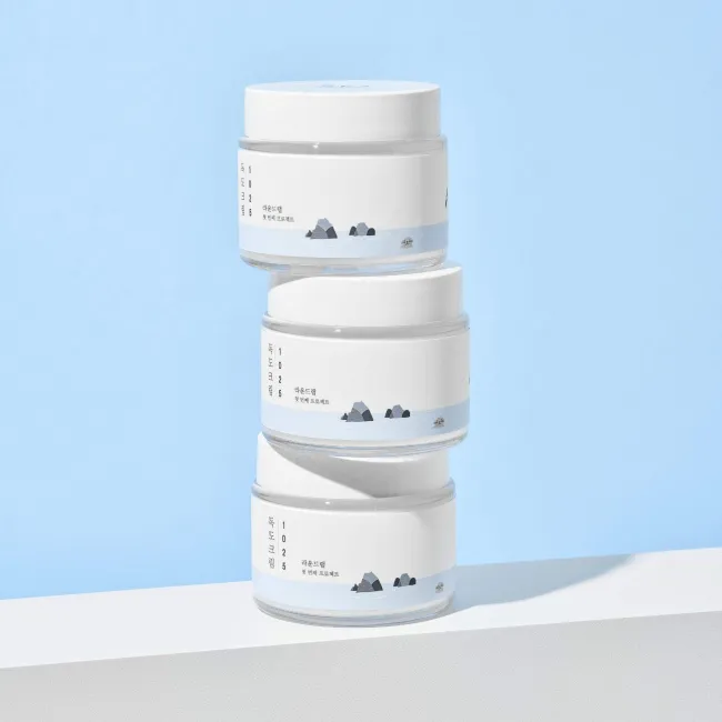 Stacked jars of clean Korean skincare cream with minimalist mountain design on labels