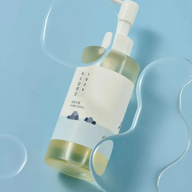 Korean skincare cleanser with pump dispenser, minimalist design, and clear liquid on blue background