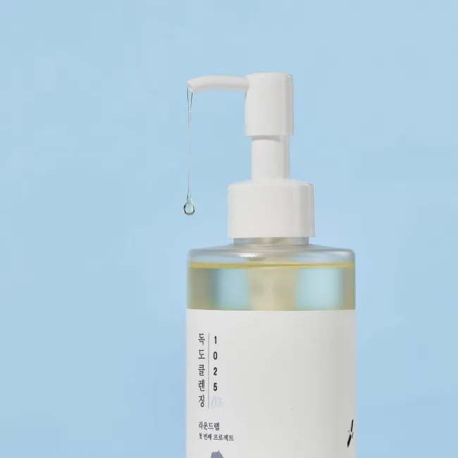 Clear skincare bottle with pump dispenser and droplet, minimalist design against blue background