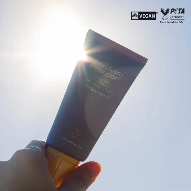 Tube of haruharu wonder BLACK RICE pure mineral relief daily sunscreen with SPF50+ PA++++ protection, for sensitive skin with sunshine at the background and vegan and Peta approval logos