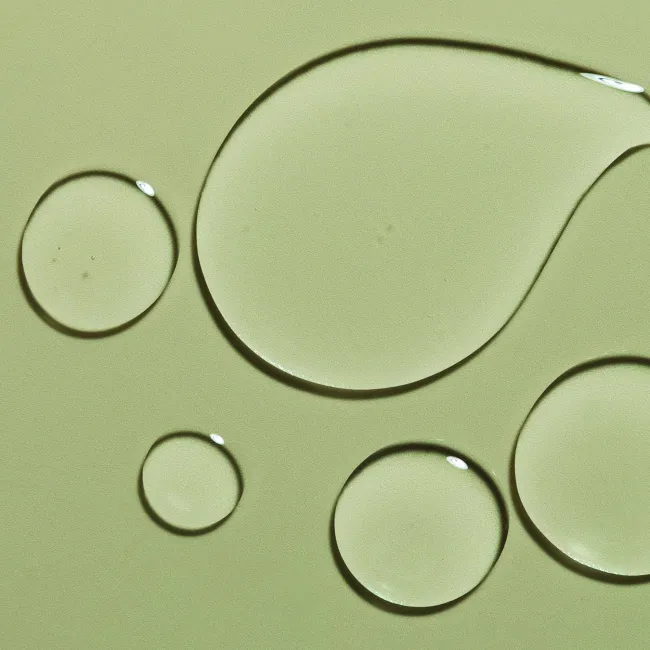 Close-up of haruharu wonder Black Rice Hyaluronic Toner Free of Alcohol & Fragrance A slightly viscous and watery toner droplets on a green surface