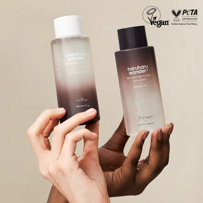 Two bottles of haruharu wonder Black Rice  Hyaluronic Toner skincare products held by hands against a beige background