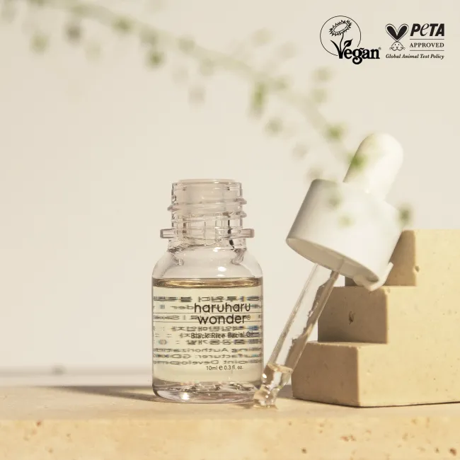 10 ml haruharu wonder black rice facial oil product with dropper and bottle on a wooden surface, featuring PETA Vegan approval logo