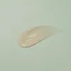 Smooth, creamy beige skincare product swatch on soft green background, showcasing clean K-Beauty texture