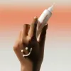 A close up of a hand holding A tube of Centella 5% Niacinamide Radiance  Gel Cream 40g on a white and orange background.