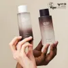 Two bottles of haruharu wonder Black Rice  Hyaluronic Toner skincare products held by hands against a beige background