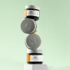 Stack of The Body Shop Glow Boosting Moisturiser jars on a light green background